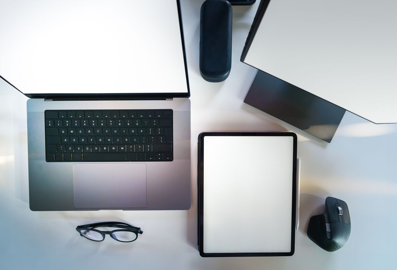Top view of a sleek modern office desk with a laptop, tablet, and accessories.